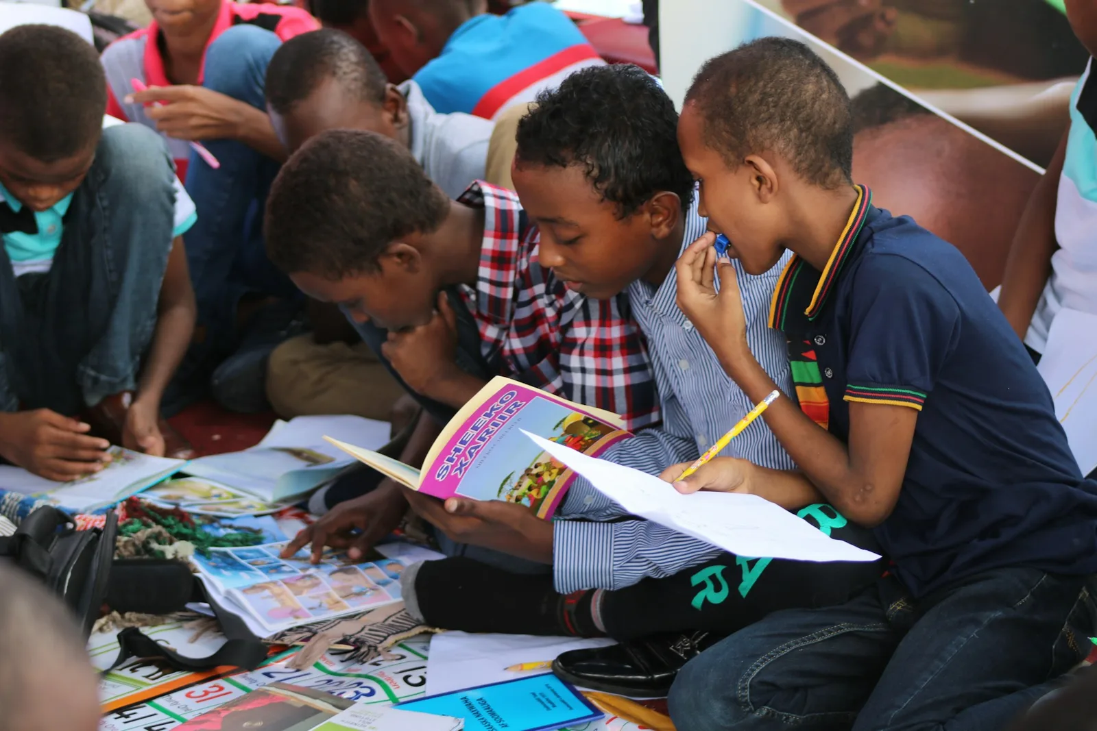Children sitting on the floor reading books and notebooks side by side