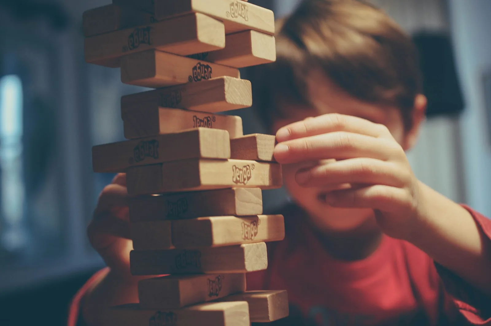 Un niño concentrado apila piezas de madera en una torre