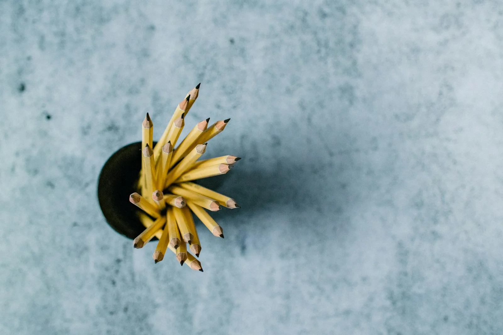 Pot of sharpened yellow pencils seen from above on a grey surface
