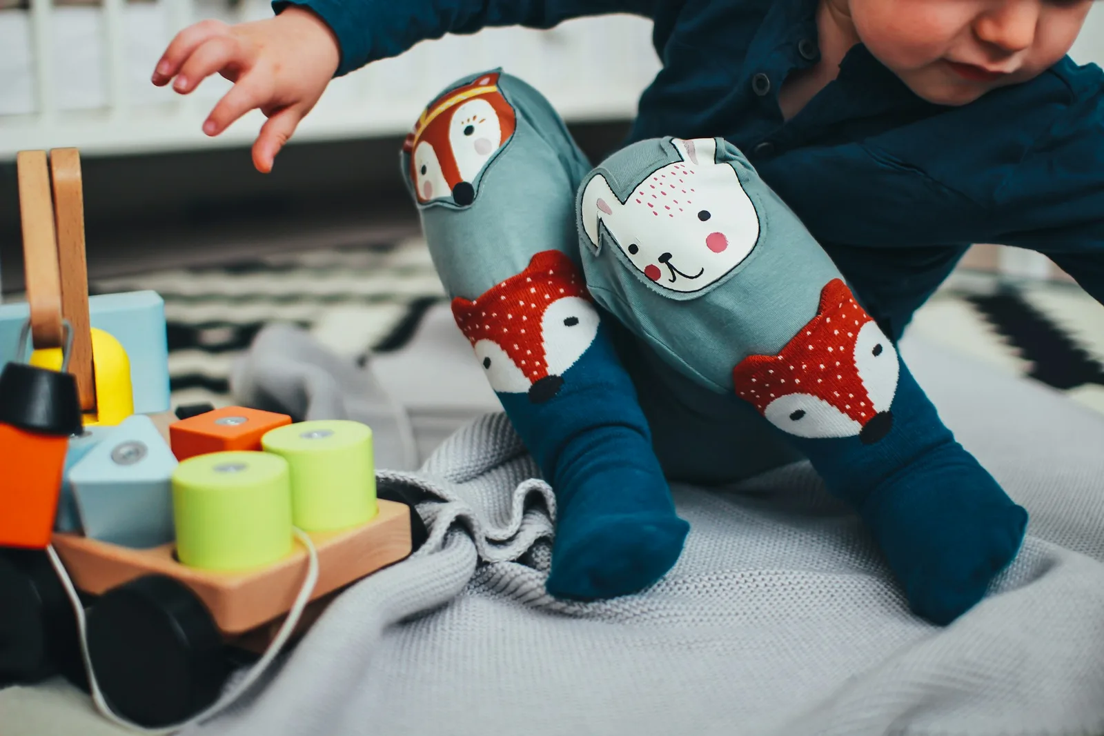 Baby crawling beside a colorful wooden toy on the rug